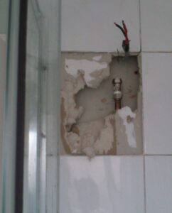 Dangerous wiring - simply removing an electrical shower and leaving the wire exposed behind the tile through the drywall