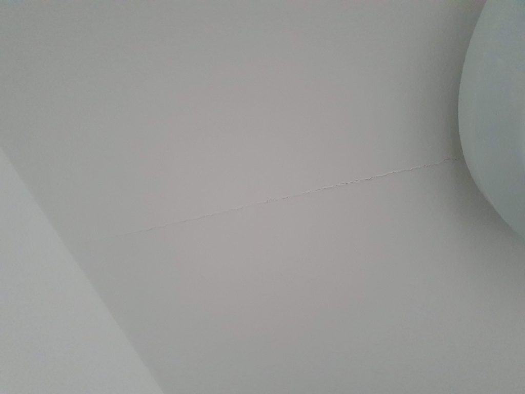 A crack on some ceiling drywall near a light