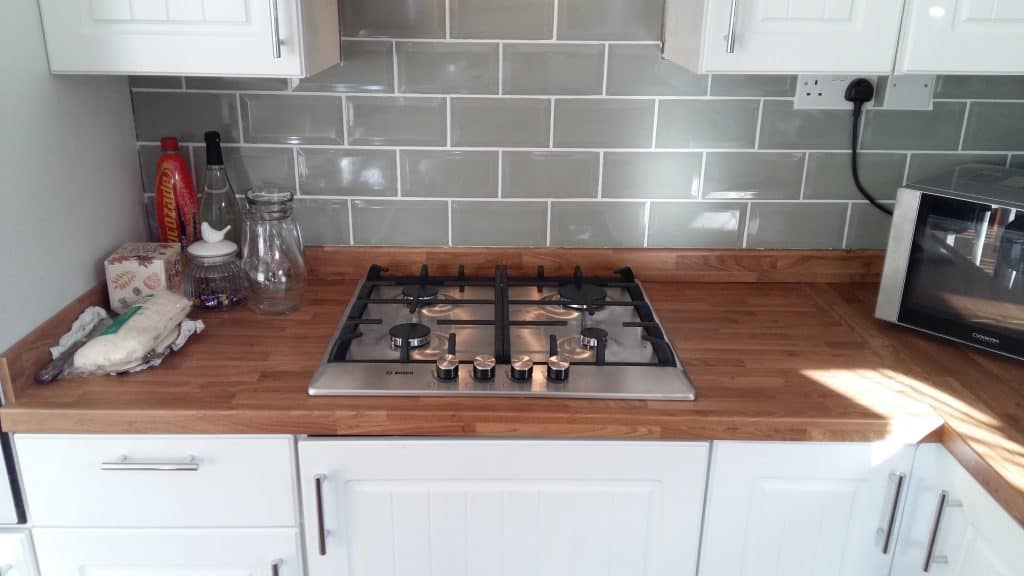 A new gas hob with extractor hood and tiled wall