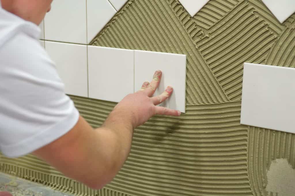 A contractor tiling a wall from the middle not from the bottom