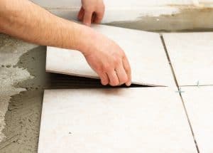 Floor tiles being laid onto a concrete floor and then tile adhesive