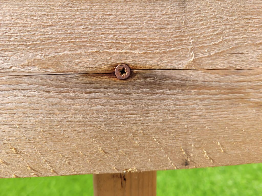Dark colored staining marks around a screw in outdoor timber